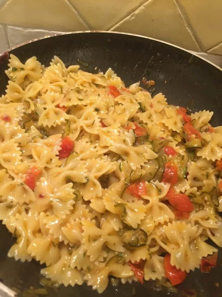 Farfalle zucchine e pomodorini servite in un piatto colorato