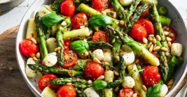 Insalata di asparagi verdi con pomodori e mozzarella su un piatto decorativo