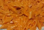 Piatto di mezze penne al baffo con salsa cremosa e prosciutto