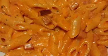 Piatto di mezze penne al baffo con salsa cremosa e prosciutto