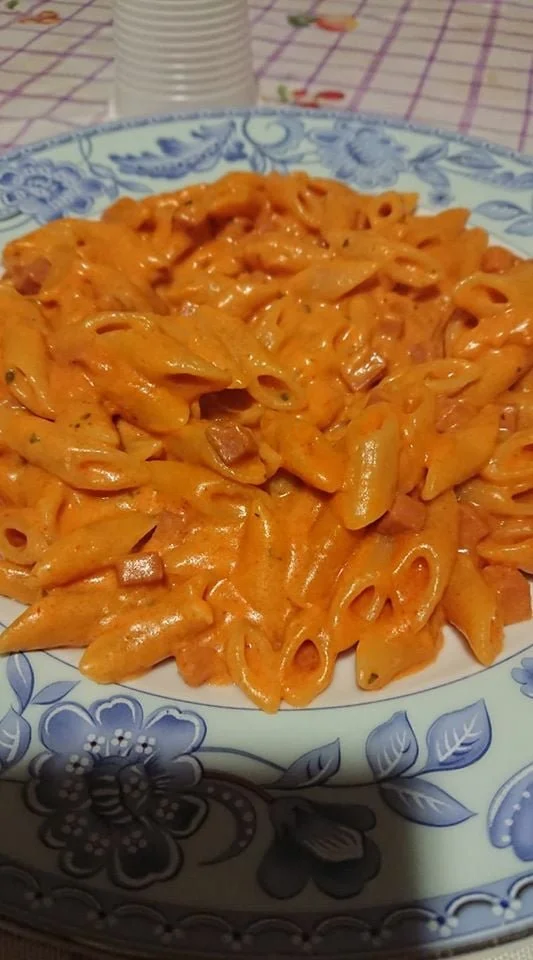 Piatto di mezze penne al baffo con salsa cremosa e prosciutto