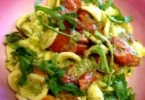 Orecchiette con pomodorini datterini e pesto di rucola in un piatto decorativo