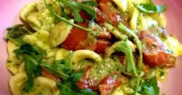 Orecchiette con pomodorini datterini e pesto di rucola in un piatto decorativo