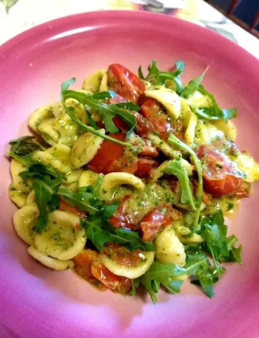 Orecchiette con pomodorini datterini e pesto di rucola in un piatto decorativo
