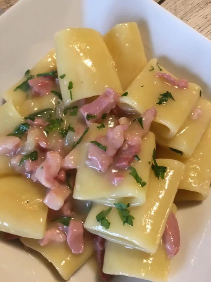 Paccheri con crema di patate e pancetta serviti in un piatto