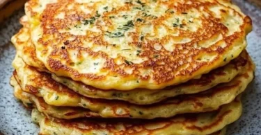 Pancake all'aglio serviti con salsa fresca e decorazione di erbe aromatiche.
