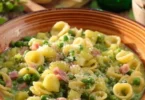 Pasta piselli e patate servita in un piatto colorato con ingredienti freschi.