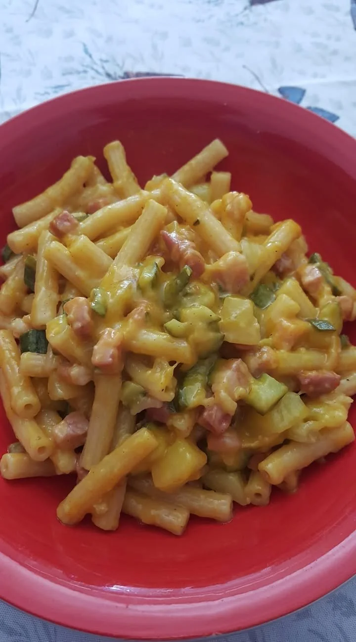 Pasta risottata con zucchina, patata, cipolla e pancetta affumicata in un piatto gourmet.