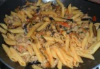Piatto di penne salsicce e melanzane con ingredienti freschi e colorati