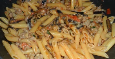 Piatto di penne salsicce e melanzane con ingredienti freschi e colorati