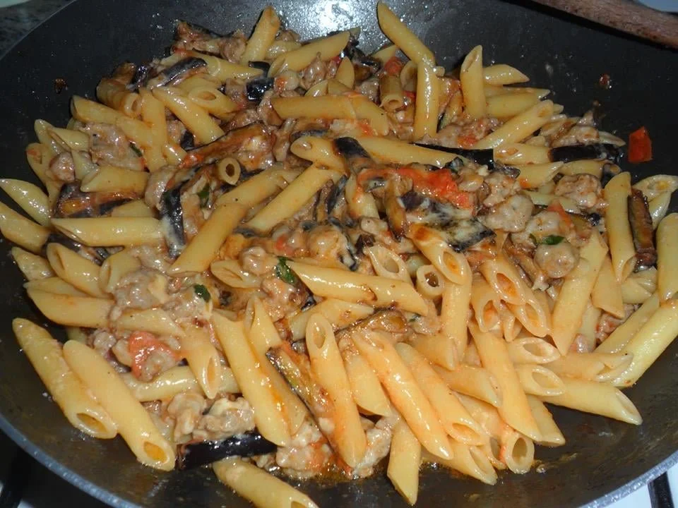 Piatto di penne salsicce e melanzane con ingredienti freschi e colorati
