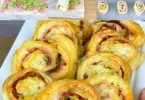Rotolo di pasta sfoglia farcito con prosciutto e zucchine, pronto da servire.