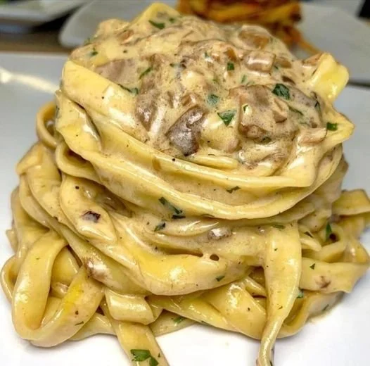 Tagliatelle con crema di parmigiano e funghi porcini in un piatto gourmet