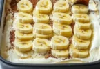 Torta di banana senza cottura decorata con fette di banana e panna