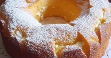 Ciambellone con ricotta e mele appena sfornato, decorato con zucchero a velo.