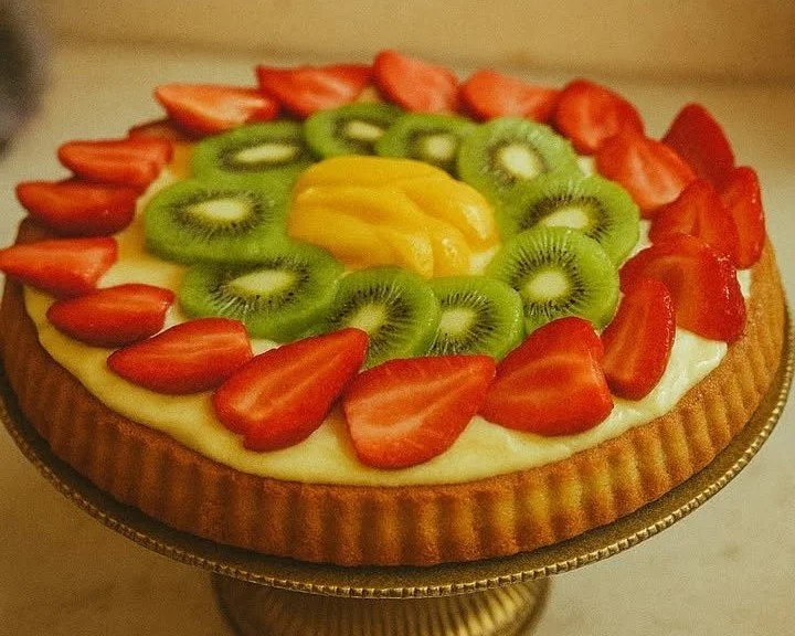Crostata morbida alla frutta decorata con frutta fresca e crema.