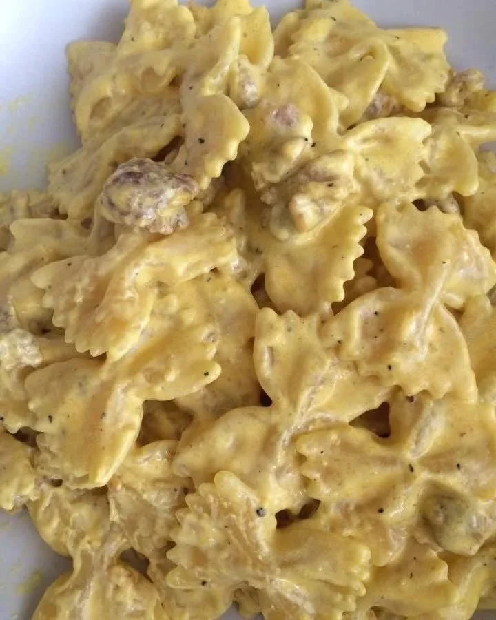 Piatto di farfalle salsiccia panna e zafferano con decorazioni gourmet