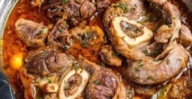 Ossobuco cucinato con verdure e spezie su un piatto, un classico della cucina italiana.