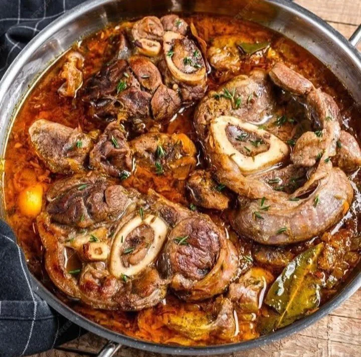 Ossobuco cucinato con verdure e spezie su un piatto, un classico della cucina italiana.