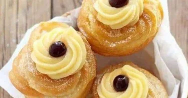 Zeppole di San Giuseppe con crema e ciliegina sul piatto