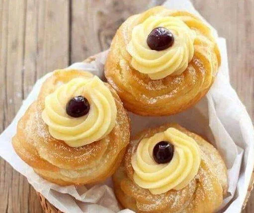 Zeppole di San Giuseppe con crema e ciliegina sul piatto