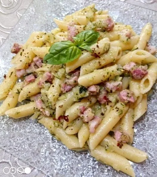 Pasta zucchine e pancetta servita con erbe fresche e formaggio grattugiato